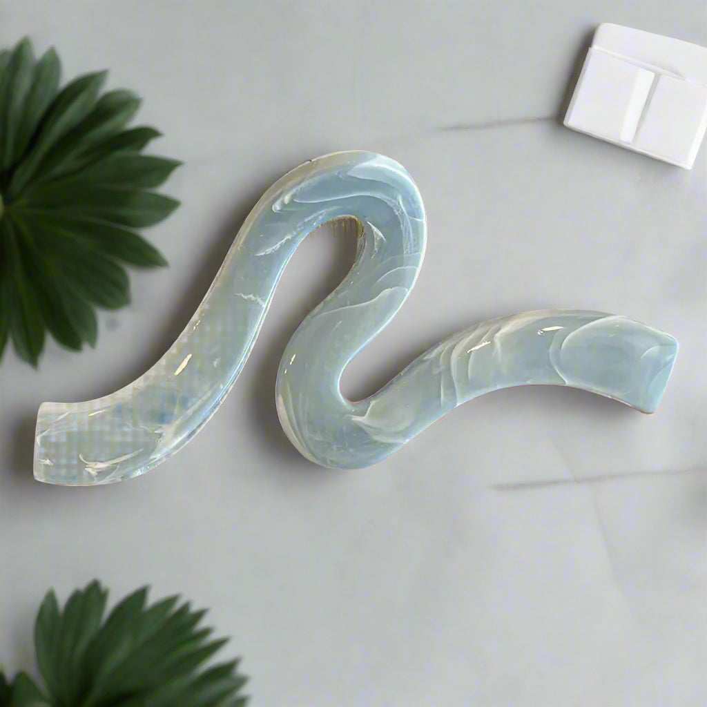 A stylish hair accessory featuring a unique wave-shaped design, perfect for securing updos with elegance. Crafted with a light blue finish, it adds a chic touch to any outfit. Ideal for medium to thick hair. 

