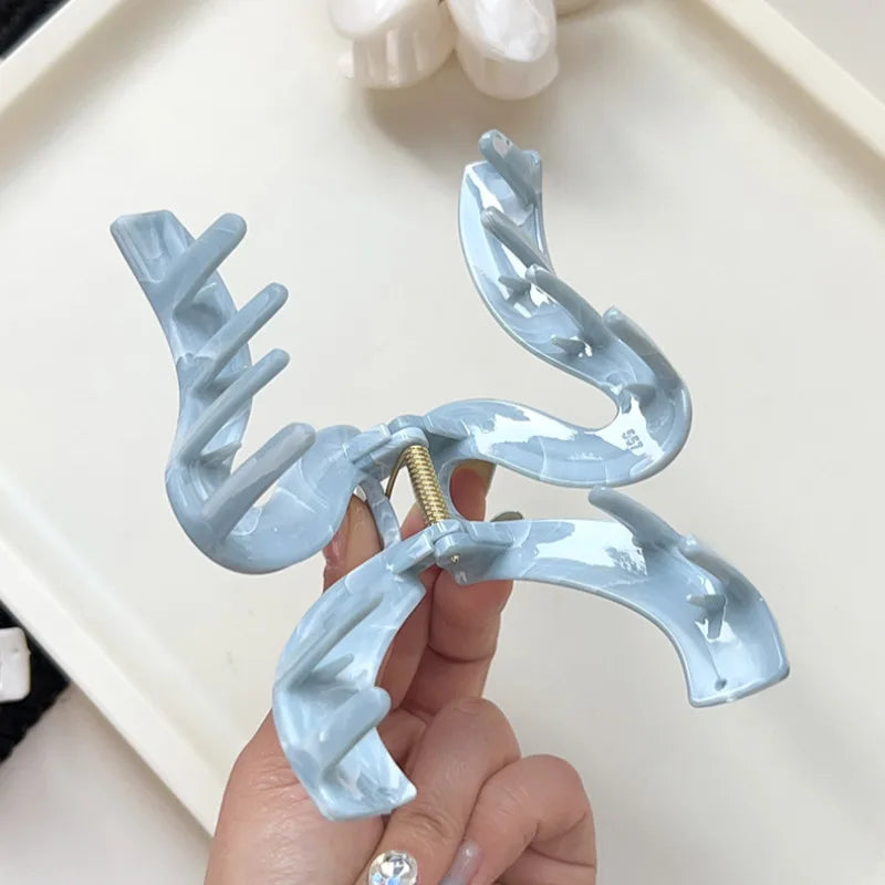 A stylish hair accessory featuring a unique wave-shaped design, perfect for securing updos with elegance. Crafted with a light blue finish, it adds a chic touch to any outfit. Ideal for medium to thick hair. 