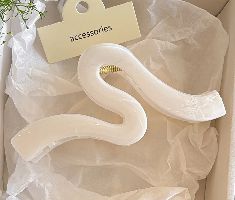 A stylish hair accessory featuring a unique wave-shaped design, perfect for securing updos with elegance. Crafted with a light blue finish, it adds a chic touch to any outfit. Ideal for medium to thick hair. 